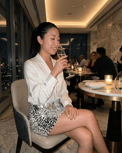 Celeste Mini Skirt worn by a woman enjoying a drink in an elegant restaurant setting, showcasing Lauven brand glamour.