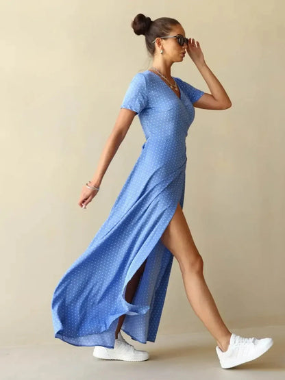 Celeste Wrap Maxi Dress in soft blue polka dots with V-neckline and thigh-high slit, styled for modern elegance.