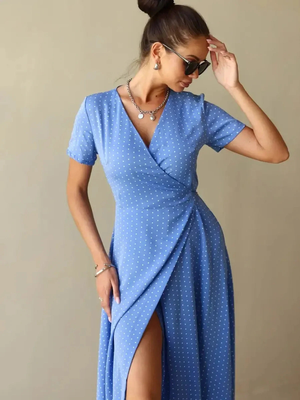 Celeste Wrap Maxi Dress in blue polka dots, featuring a V-neckline and thigh-high slit, perfect for day or evening wear.