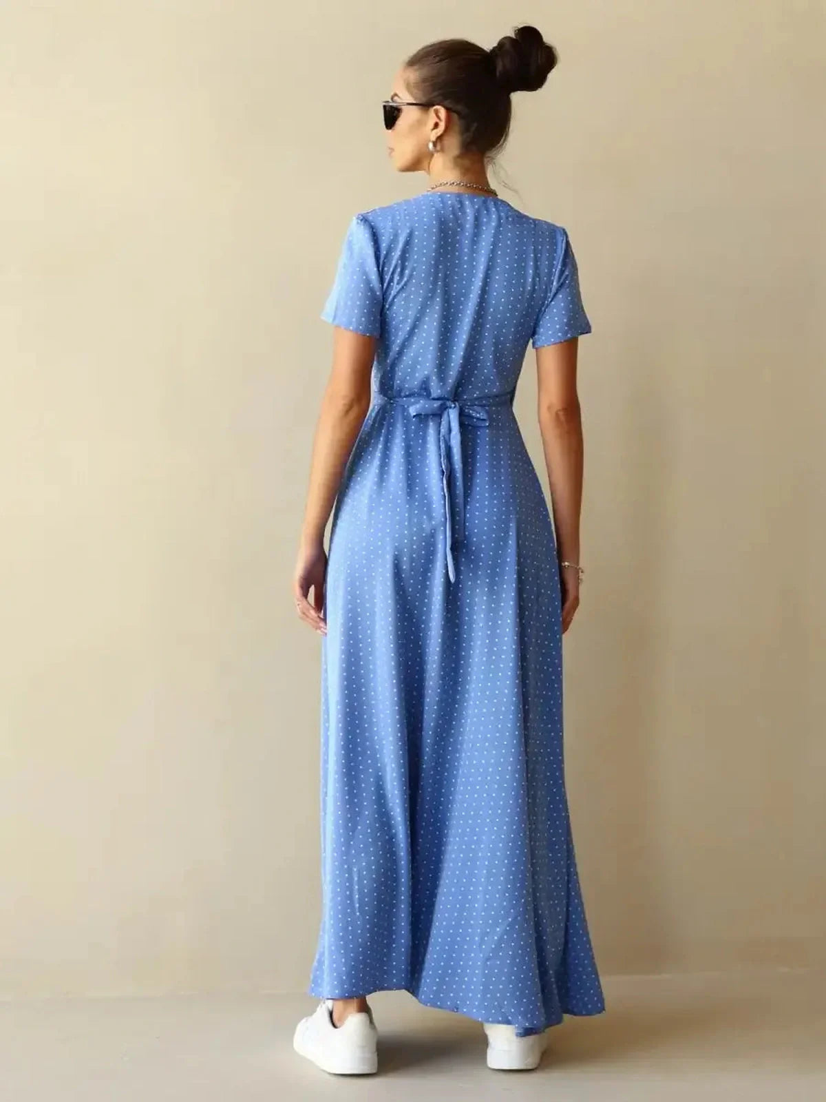 Back view of Celeste Wrap Maxi Dress in soft blue polka dots, showcasing a tied waist and relaxed fit.