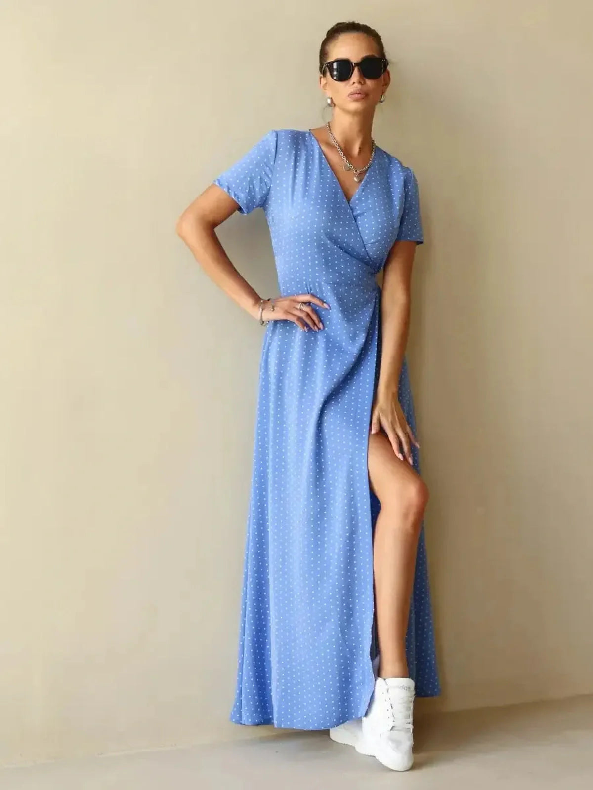 Celeste Wrap Maxi Dress in soft blue with polka dots, featuring a V-neckline and thigh-high slit for an elegant look.