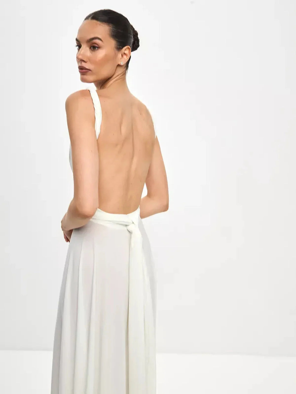 Back view of a model wearing a Celeste Wrap Maxi Dress with a plunging back and elegant flowing skirt.