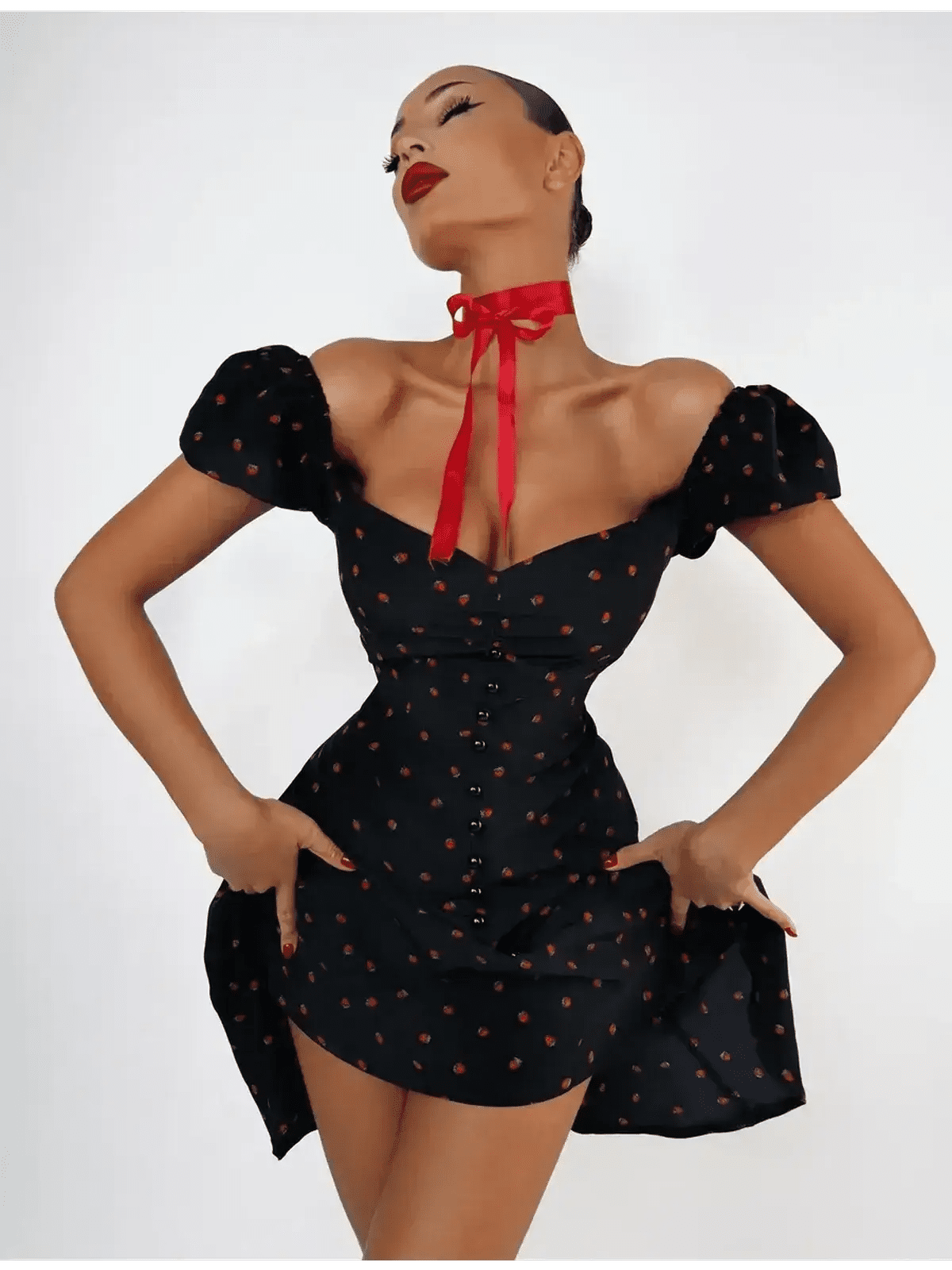 Woman modeling a Cherry Kiss Mini Dress featuring cherry print, puff sleeves, and a sweetheart neckline.