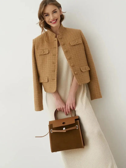Model in a tan jacket paired with a ribbed maxi dress, holding a brown handbag, showcasing a chic summer outfit.