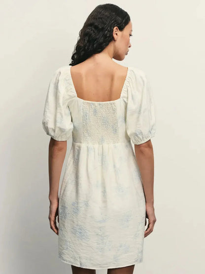 Back view of the Cloud Bloom white mini dress showcasing puff sleeves and floral pattern, highlighting its elegant design.