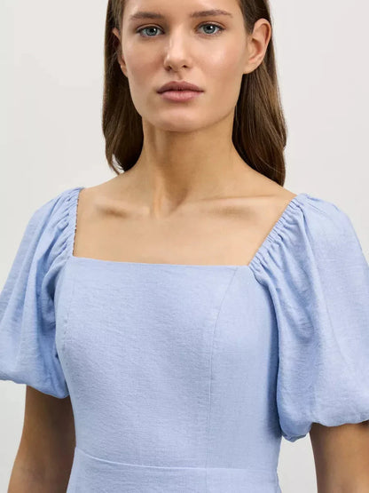 Close-up of a model wearing the Cloudline Mini dress in light blue featuring a square neckline and puff sleeves.
