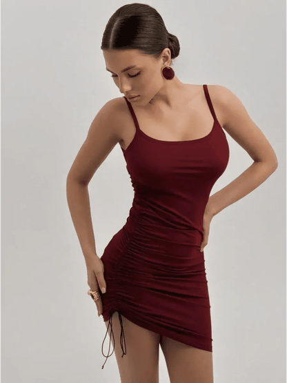 Model in a fitted crimson mini dress with spaghetti straps and side ruching, perfect for summer and special occasions.