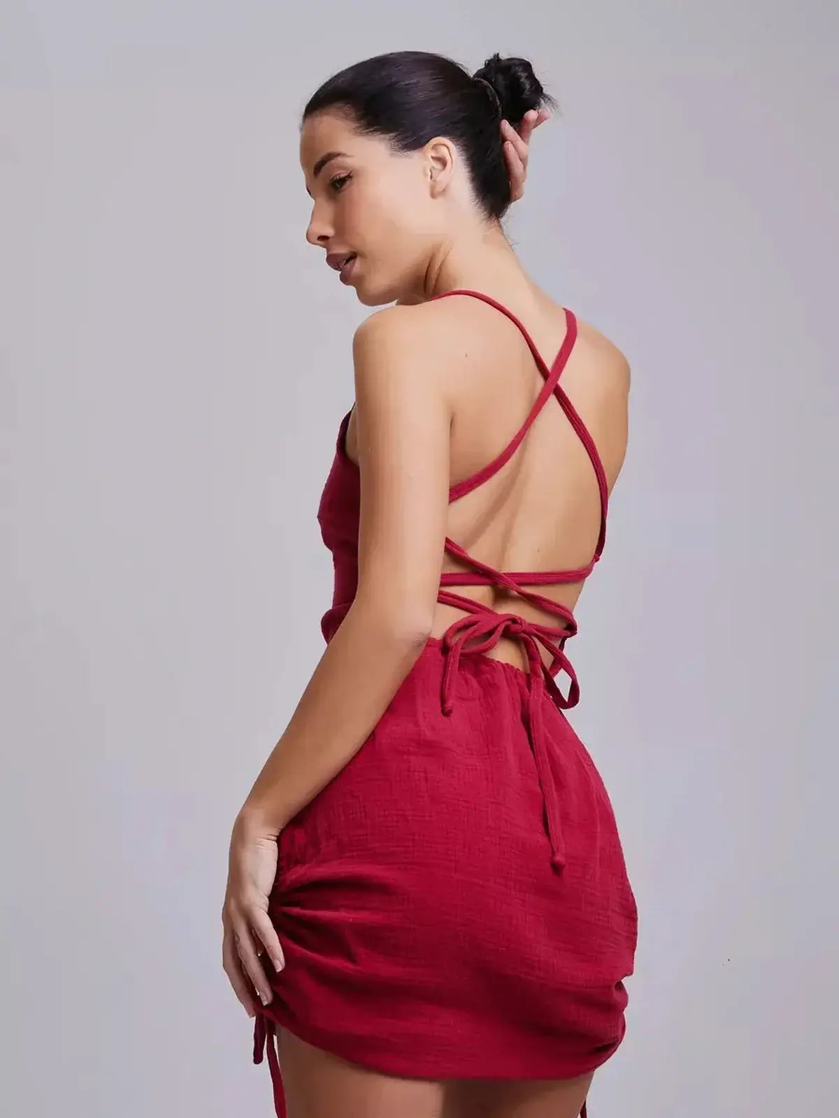 Model showcasing the back of the Crimson Muse dress by Lauven, featuring an intricate lace-up design.