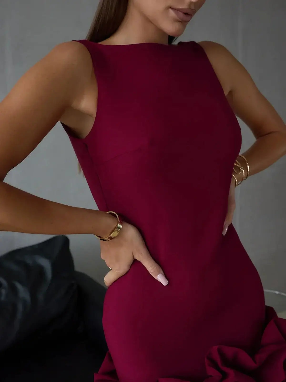 Model wearing a burgundy sleeveless bodycon mini dress featuring a U-neckline and ruffle hem, perfect for summer occasions.
