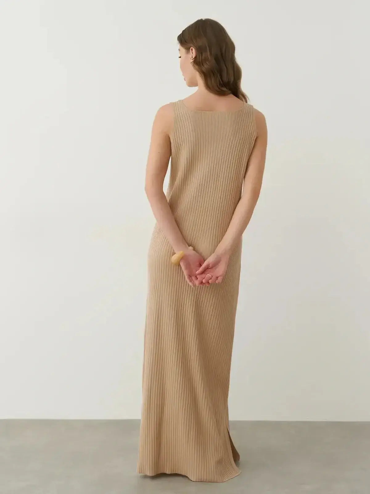 Back view of the Desert Aura Maxi Dress, showcasing its ribbed texture and elegant longline silhouette in a soft neutral tone.