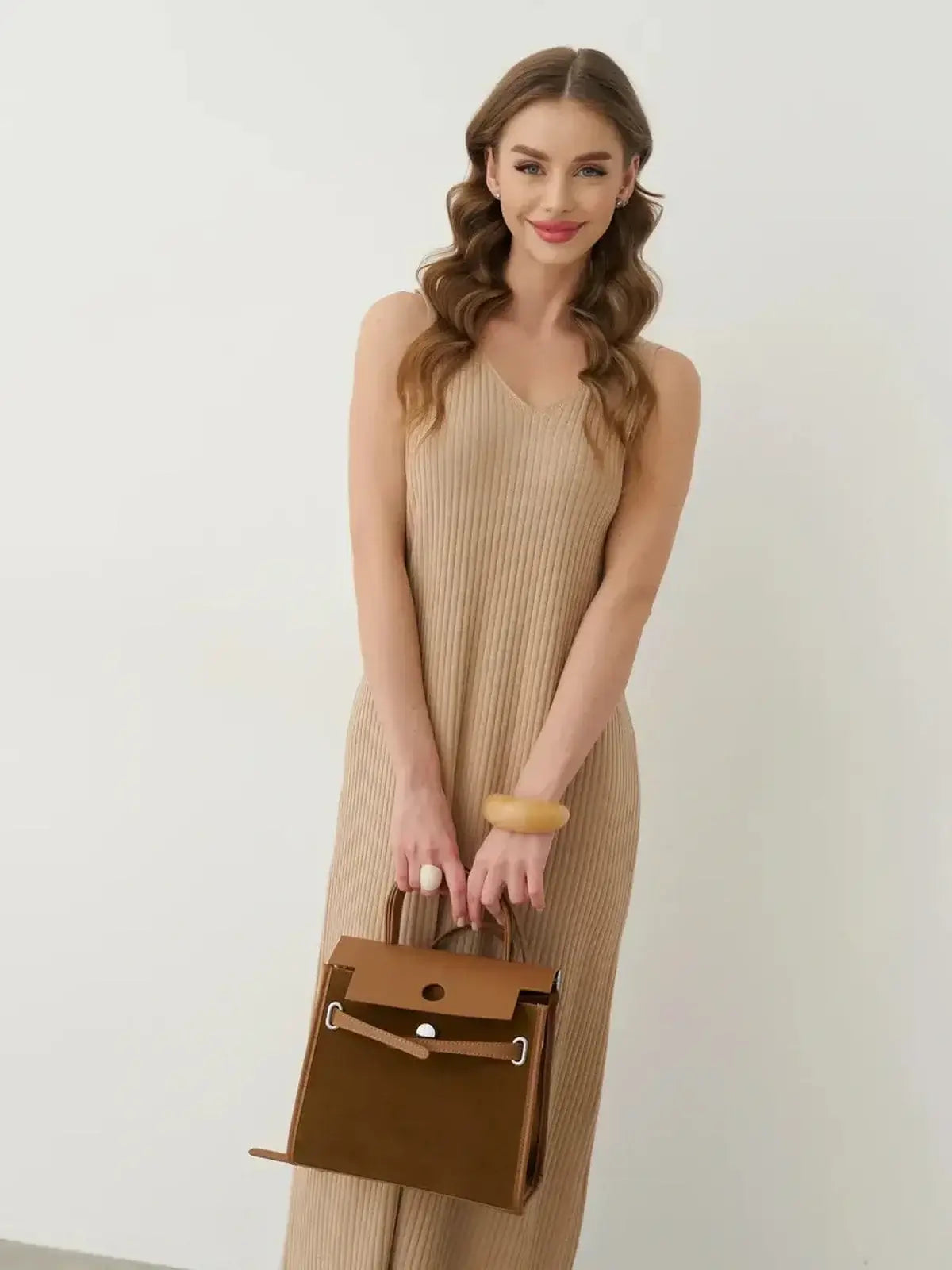 Model in Desert Aura Maxi Dress holding a stylish handbag, showcasing summer elegance and ease with a neutral knit design.