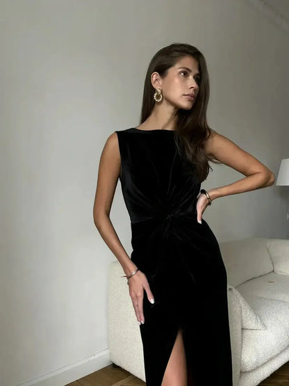 Model showcasing Eclipse Maxi Dress in black velvet, featuring a draped knot and thigh-high slit against a neutral backdrop.