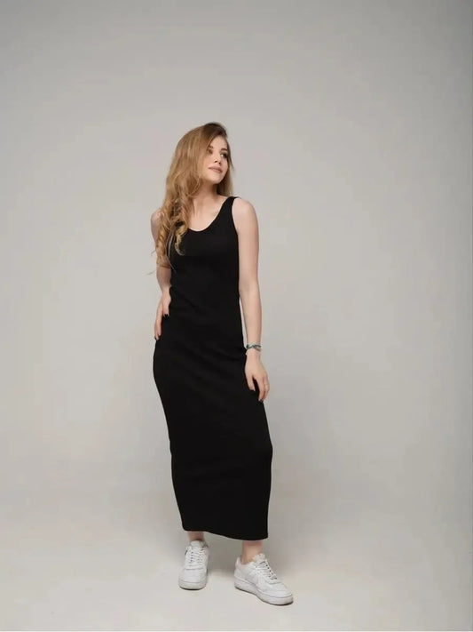 Model wearing the Eclipse Maxi Dress, a sleek black sleeveless dress, styled with white sneakers for a chic look.