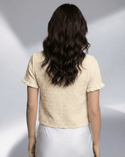 Back view of a woman wearing the Elara Cardigan by Lauven, showcasing its short sleeves and textured design.