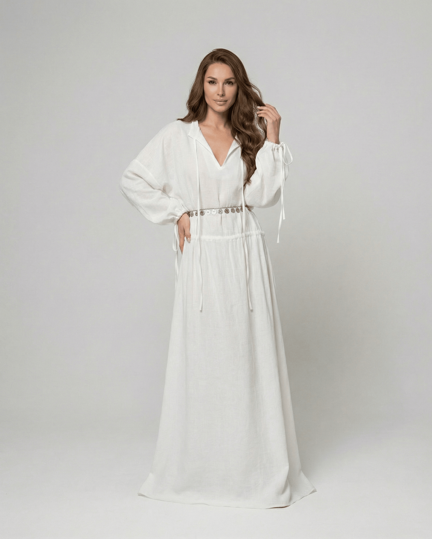 Woman in white Elara Maxi Dress by Lauven with adjustable waist and long sleeves.