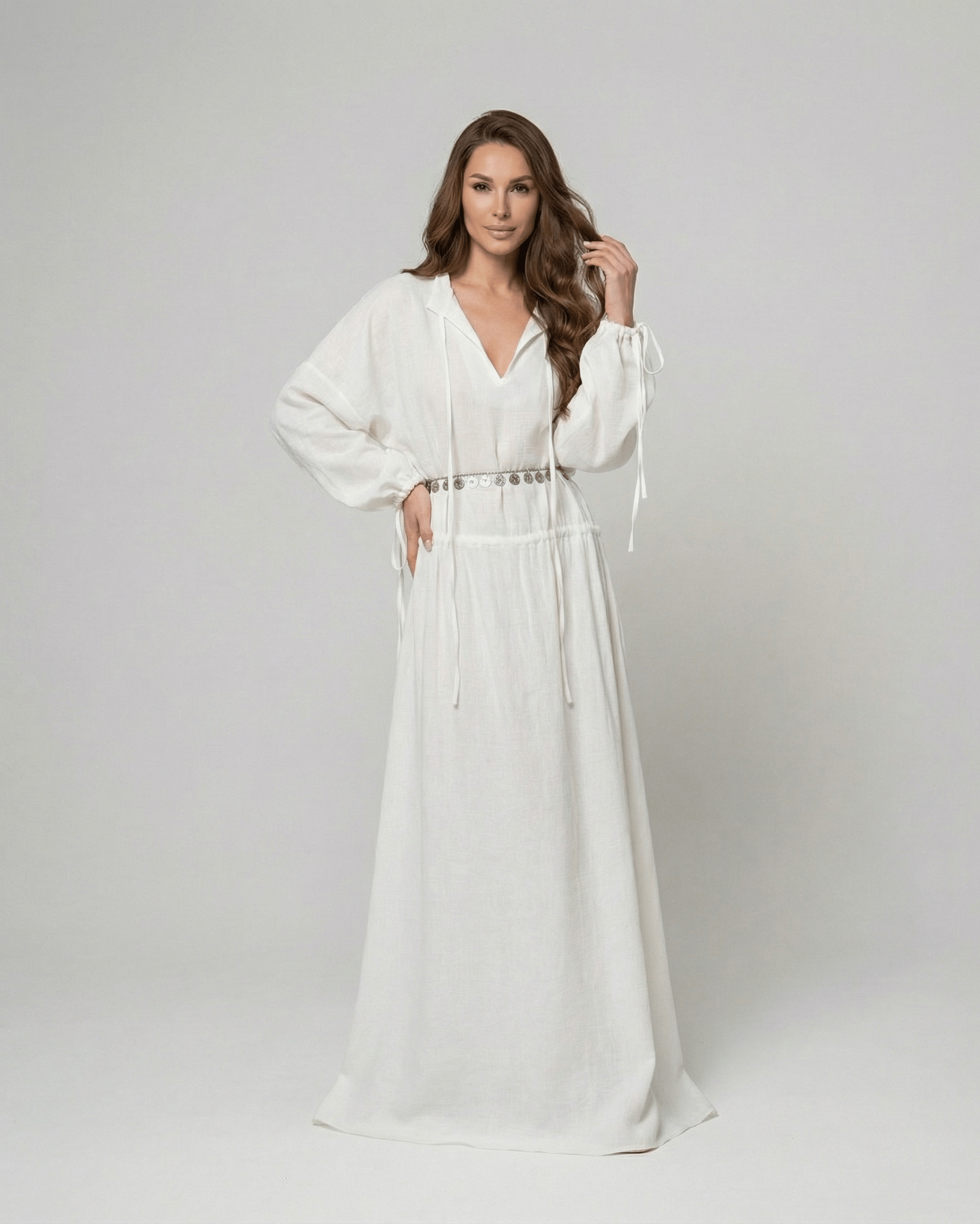 Woman in white Elara Maxi Dress by Lauven with adjustable waist and long sleeves.