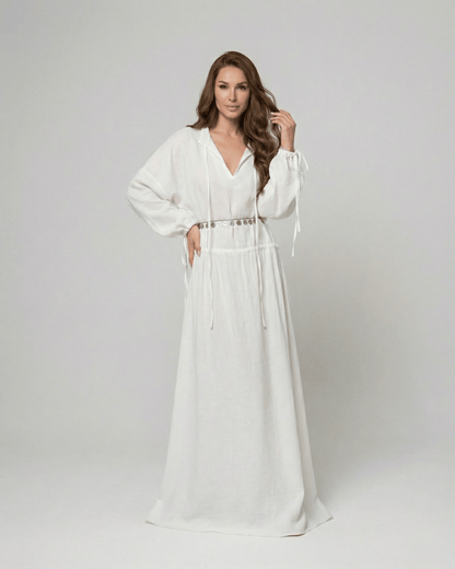 Woman in white Elara Maxi Dress by Lauven with adjustable waist and long sleeves.