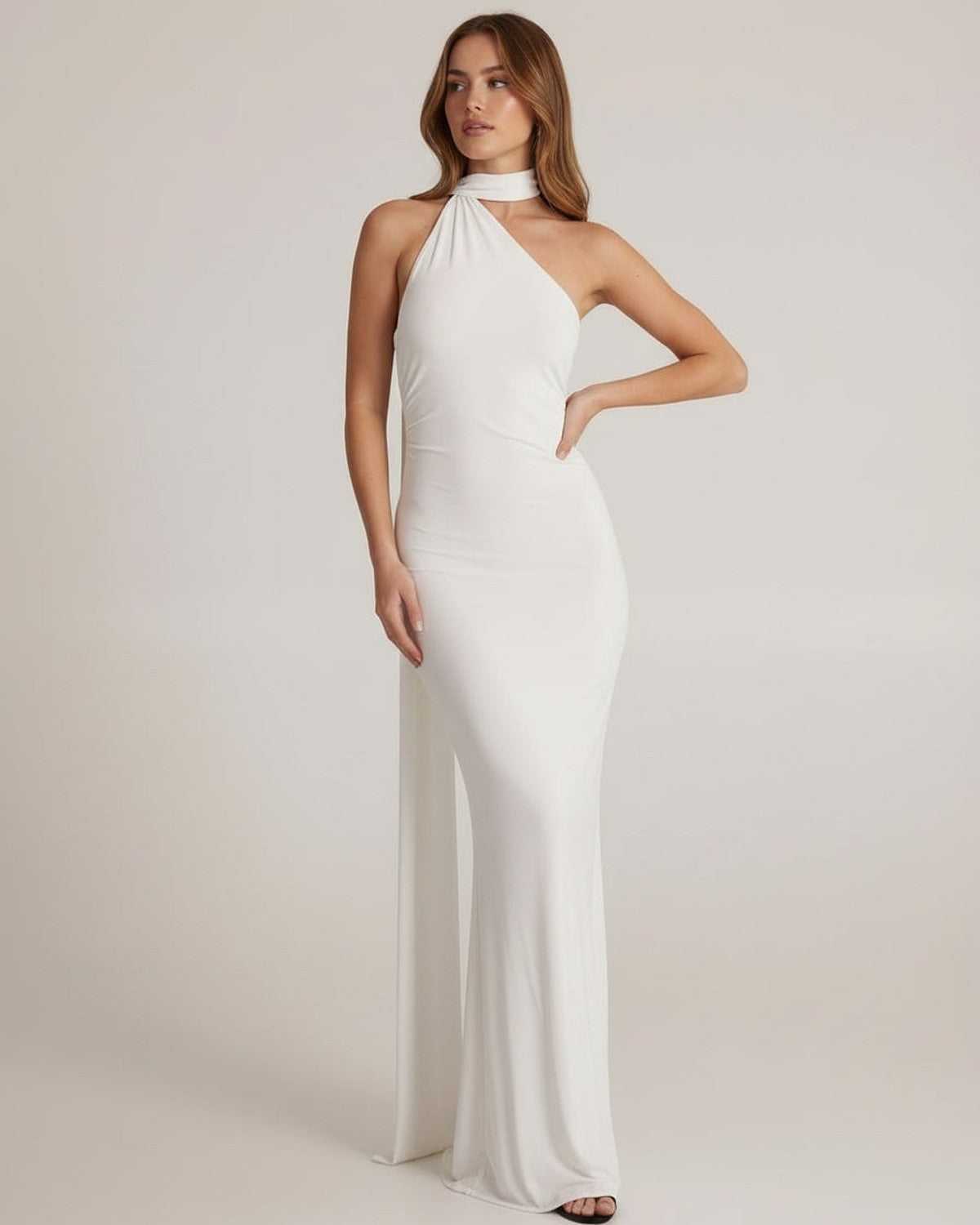 Elara Maxi Dress model wearing a white halter neck dress with open back, showcasing its elegant design by Lauven.