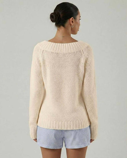 Back view of a woman wearing the Elara Sweater by Lauven, showcasing its beige color and rib knit detail.