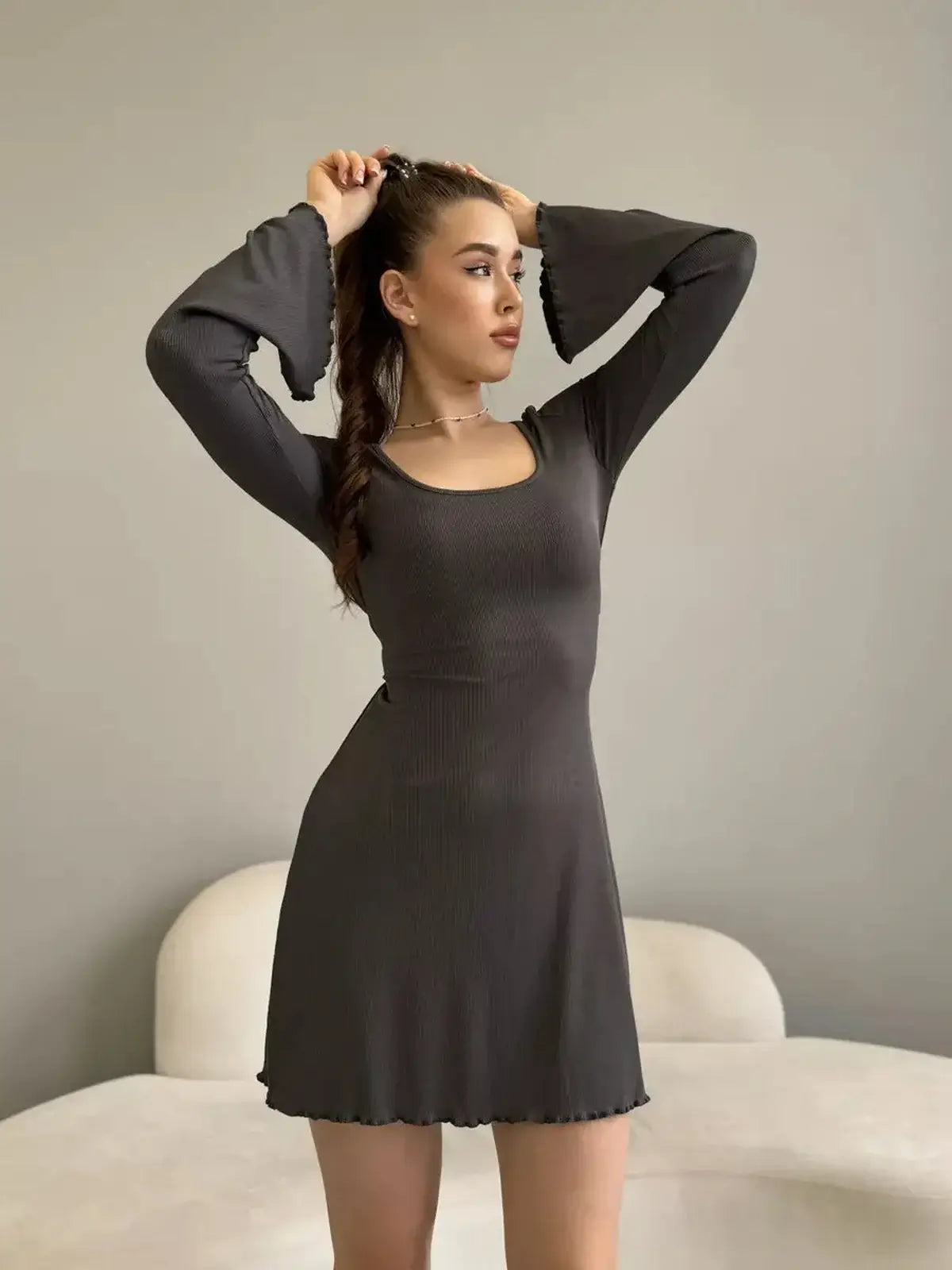 Model showcasing the Shadow Flare mini dress with long bell sleeves and a square neckline, perfect for summer events.