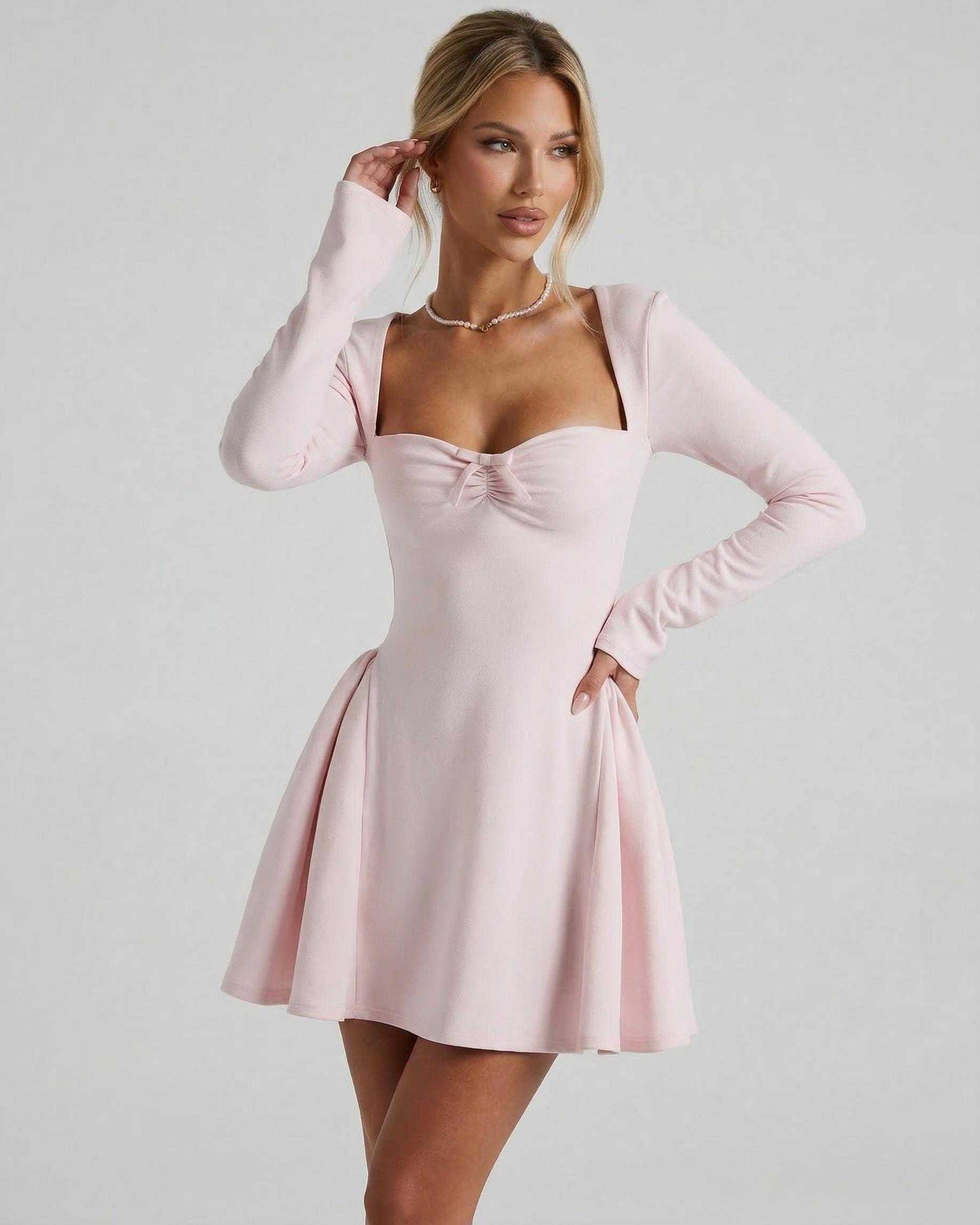 Elvire Mini Dress features a light pink color, long sleeves, ruched neckline, and flared skirt by Lauven.