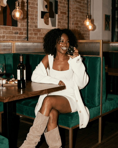 Elysia Mini Dress by Lauven, chic fitted knit dress styled with a cardigan, enjoying a drink in a stylish setting.