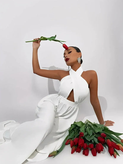 Elysian Jumpsuit by Lauven, featuring a halter neck, cut-out bodice, and wide-leg silhouette, complemented by red tulips.