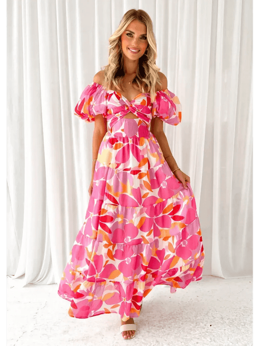 Model wearing the vibrant Flora Muse Maxi Dress featuring off-shoulder sleeves and floral prints in pink and orange.