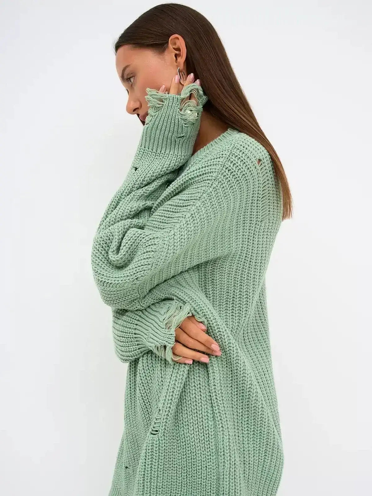 Model wearing a soft mint green Frost Knit Mini sweater dress with distressed accents, showcasing oversized fit and chunky knit texture.