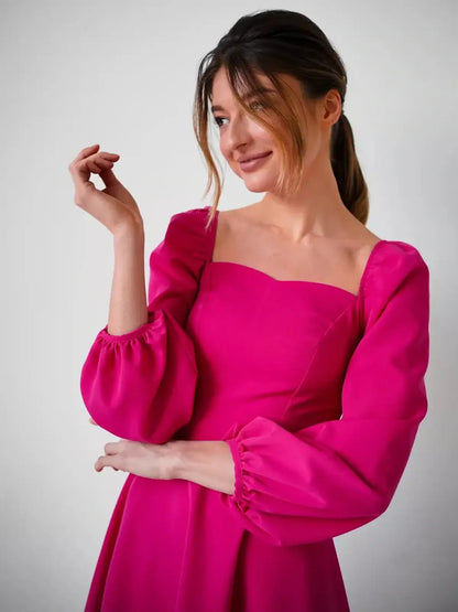 Model wearing a fuchsia bloom mini dress with a square neckline and long puff sleeves, perfect for weddings and parties.