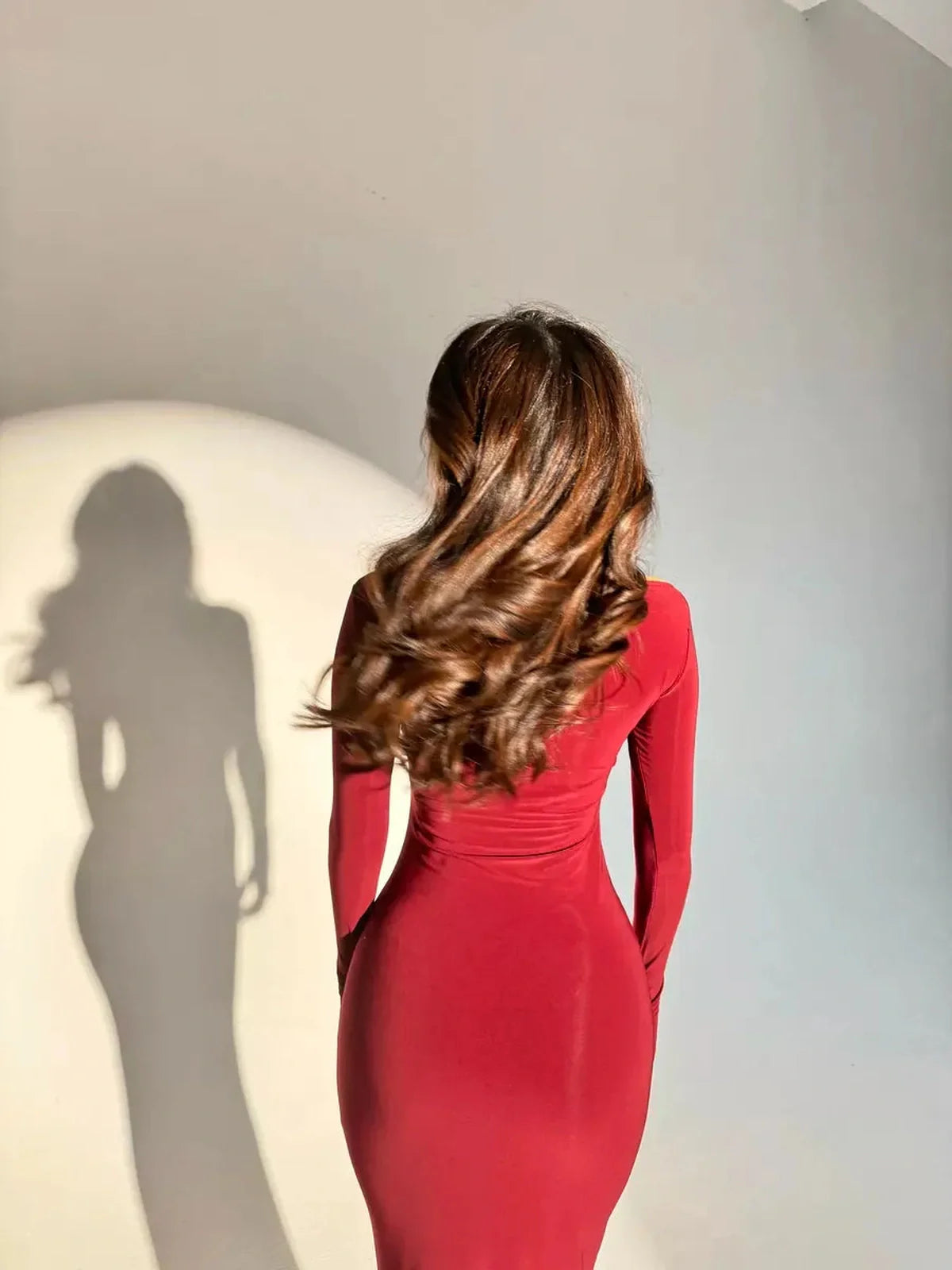 Woman wearing a garnet sculpt maxi dress, showcasing a smoothing silhouette and elegant long sleeves.