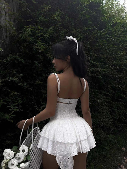 Elegant white mini dress with lace details and adjustable straps, perfect for summer occasions or as a wedding guest dress.