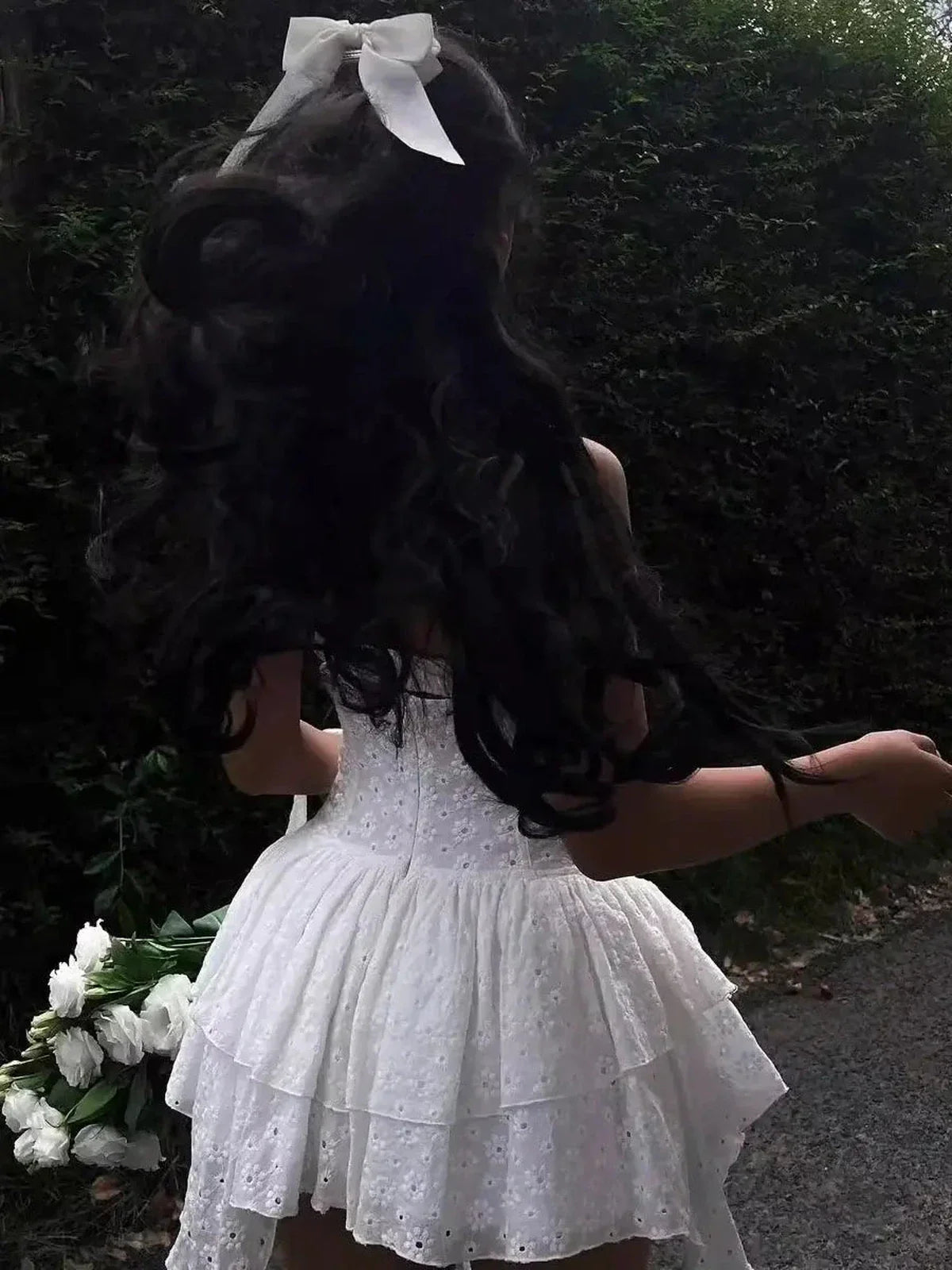 A woman in a white mini dress with lace detail, showcasing a playful and elegant summer look, perfect for weddings or special occasions.