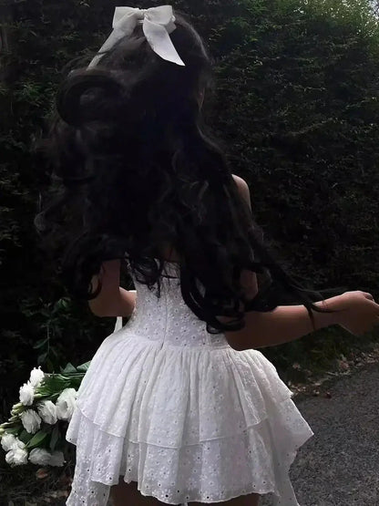 A woman in a white mini dress with lace detail, showcasing a playful and elegant summer look, perfect for weddings or special occasions.