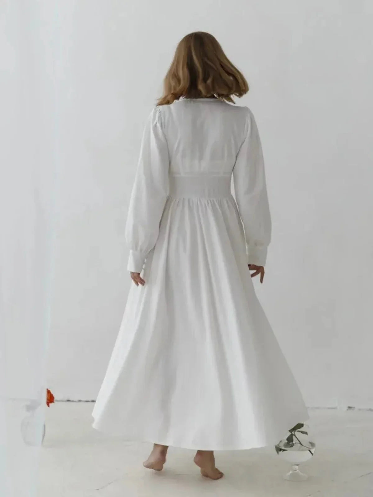 Woman in a white heirloom maxi dress with vintage-inspired details, showcasing a graceful back view.