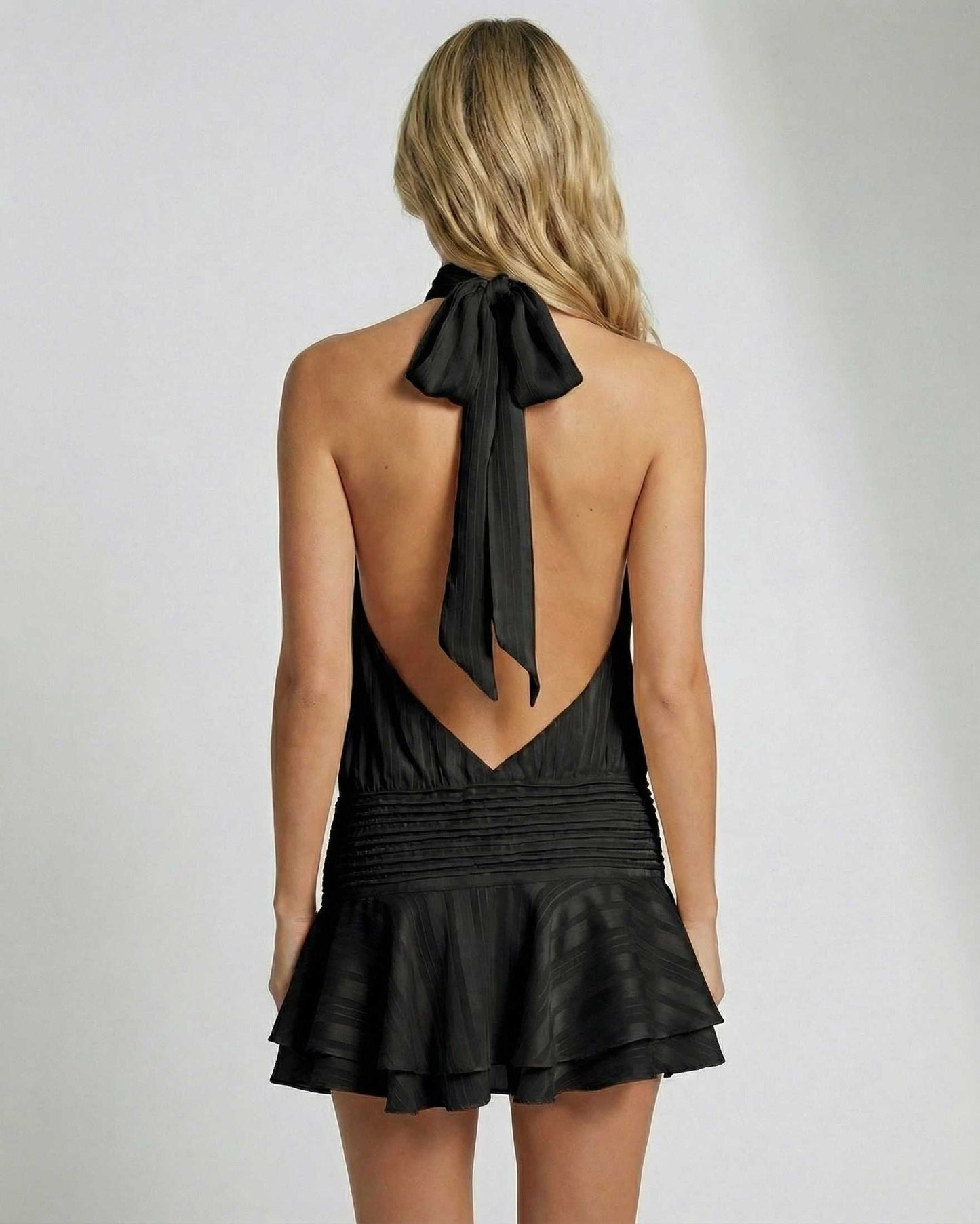 Noiré Mini Dress by Lauven, pleated chiffon halter mini dress in black with an open back and bow detailing.