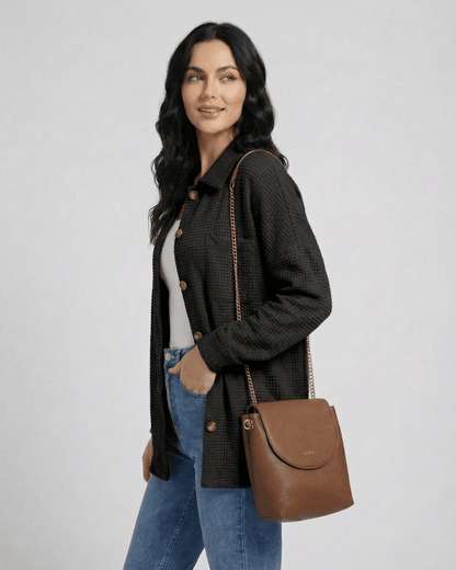 Model wearing Milano Jacket by Lauven, a women's black waffle knit jacket, paired with a brown handbag.