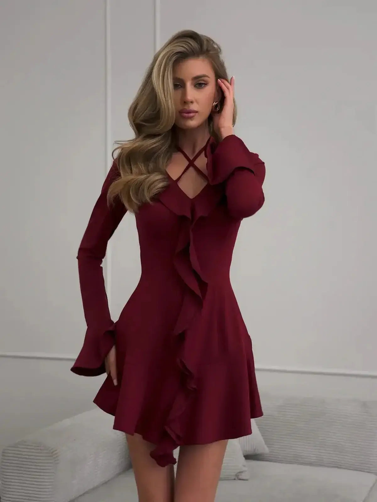 Stylish burgundy mini dress with long sleeves, V-neckline, and ruffle detailing, perfect for cocktail or summer events.