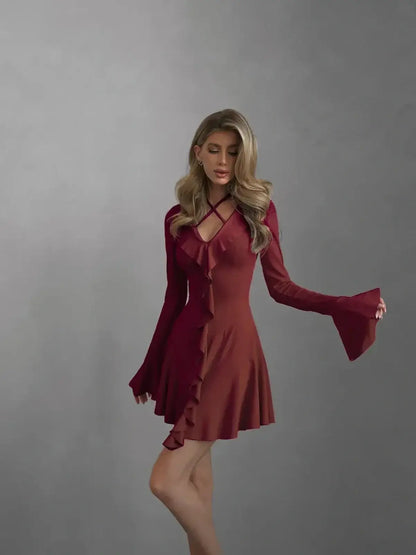 Rich burgundy long sleeve mini dress with cross-strap detailing and ruffles, perfect for weddings or parties.