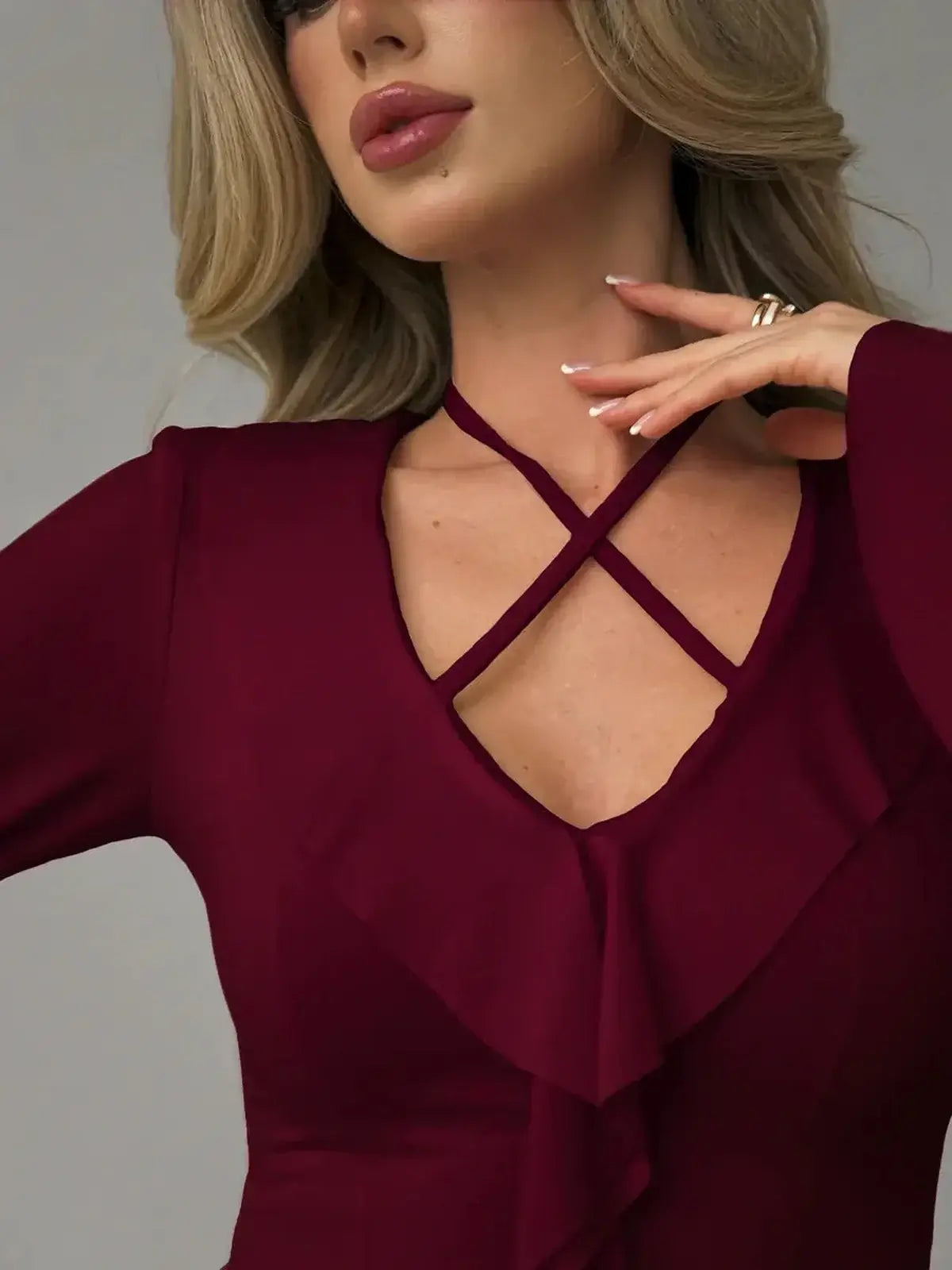 Close-up of the Velvet Rush burgundy mini dress featuring a V-neckline and cross-strap detailing with ruffles.