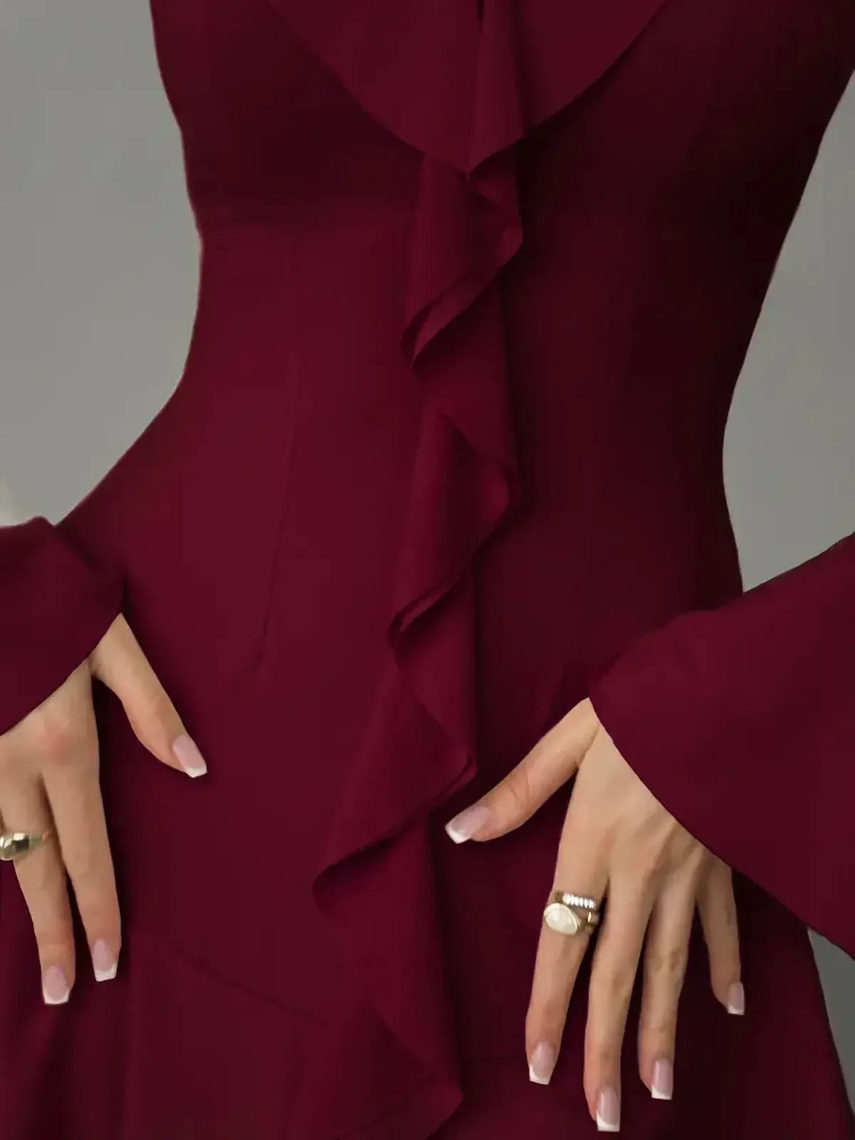 Close-up of a burgundy long sleeve mini dress featuring cascading ruffles and flared sleeves for a refined look.