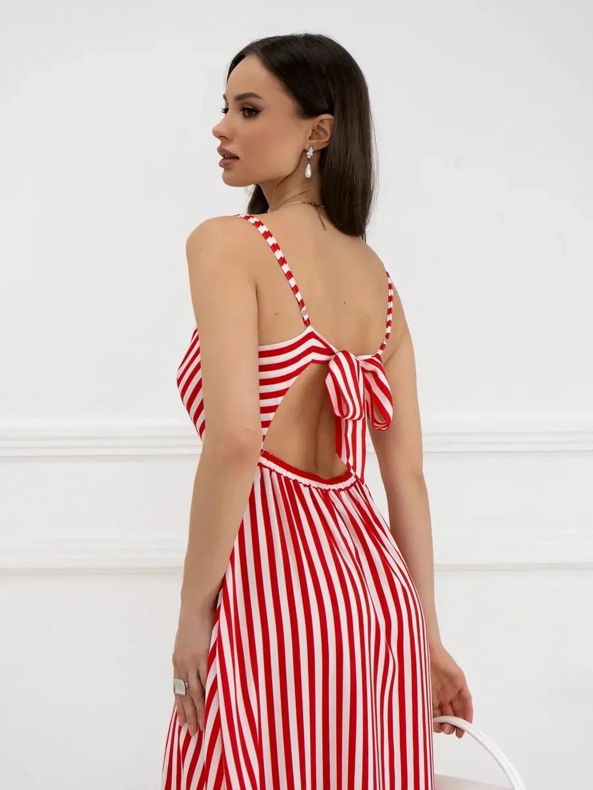 Back view of a woman wearing the Maxi Dress Riviera Curve with red and white stripes and a playful bow tie detail.