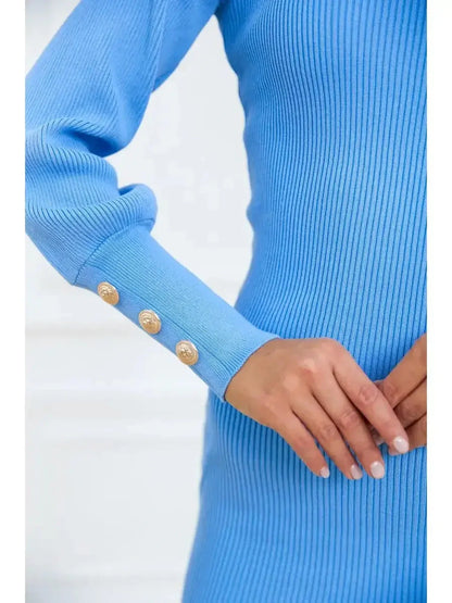 Close-up of a woman's hand wearing a long sleeve azure blue mini dress with gold-tone button details.