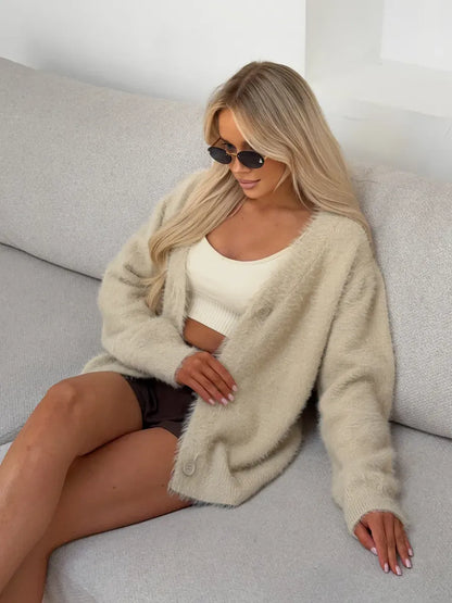 Woman wearing Sable Cardigan by Lauven, an oversized light beige fluffy knit with button closure.