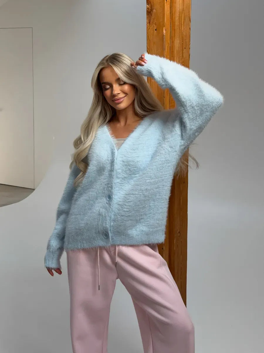 A woman wearing a light blue fluffy Azure Cardigan by Lauven, styled with relaxed pink pants.