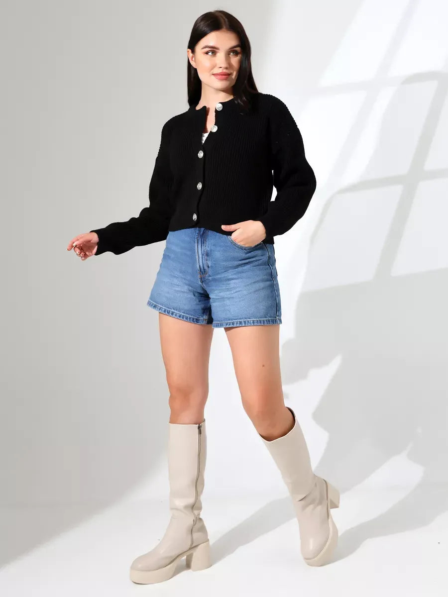 Model wearing the Nova Cardigan by Lauven, a sleek black knitwear piece, paired with denim shorts.