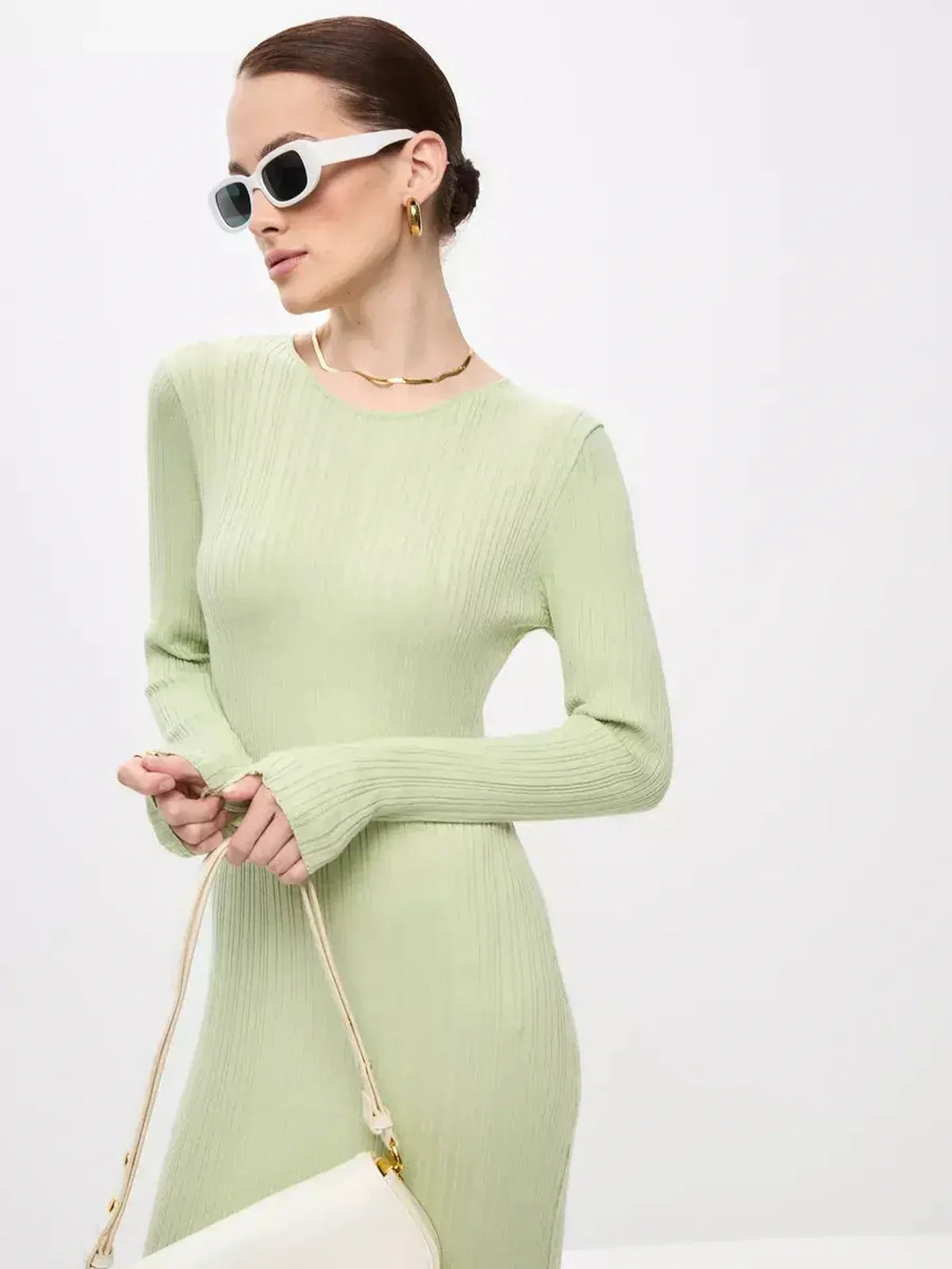 Model in a light green Celery Luxe Maxi Dress with long sleeves and a sculpted fit, accessorized with white sunglasses.