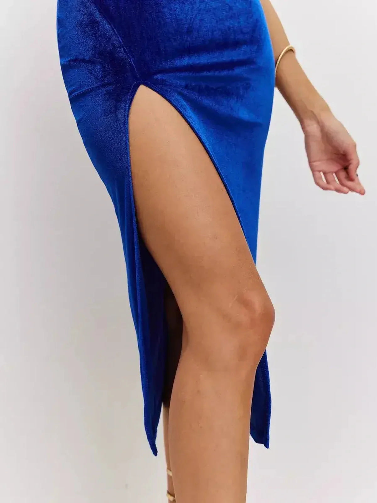 Close-up of a thigh-high slit on a luxe blue velvet midi dress, showcasing a striking silhouette and elegant design.