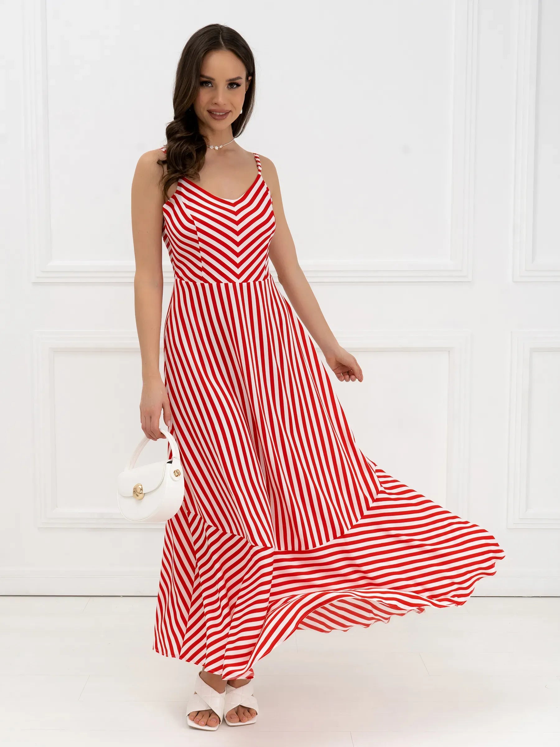 Maxi Dress Riviera Curve featuring red-and-white stripes and a breezy tiered hem, modeled in a bright, elegant setting.