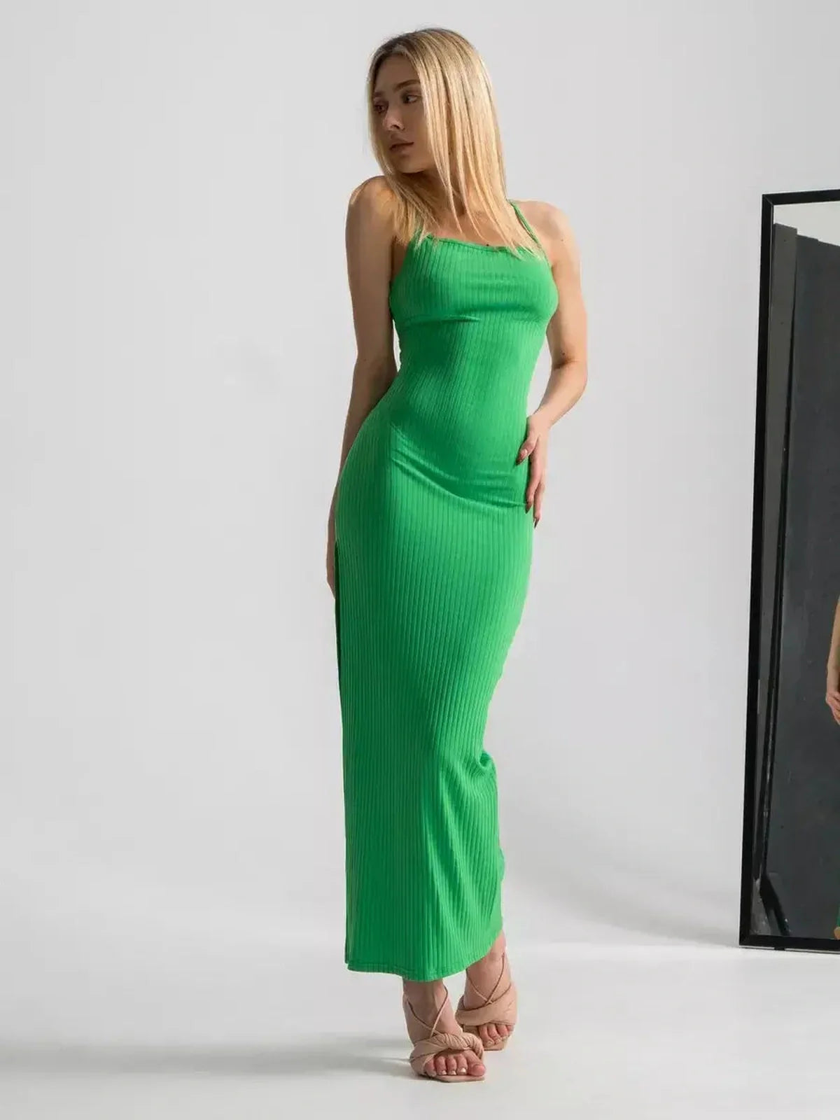 Model wearing a sleek maxi dress in vibrant emerald green with strappy back and body-hugging fit.